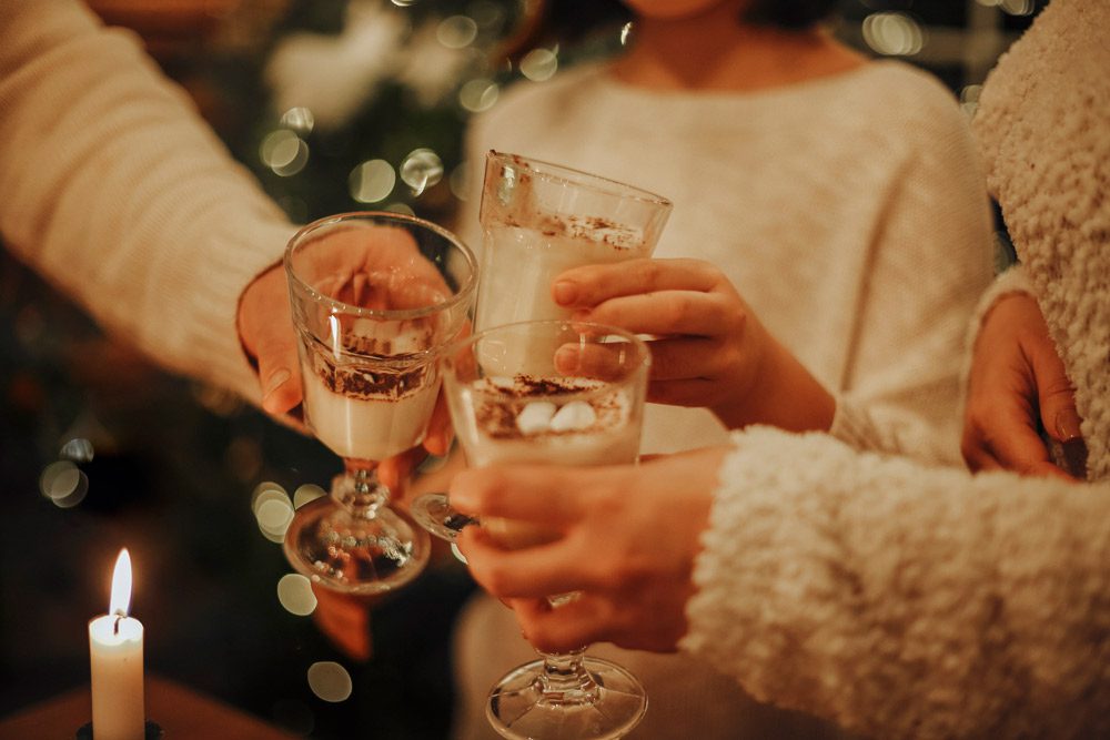 Family drinking egg nogg by Christmas tree.