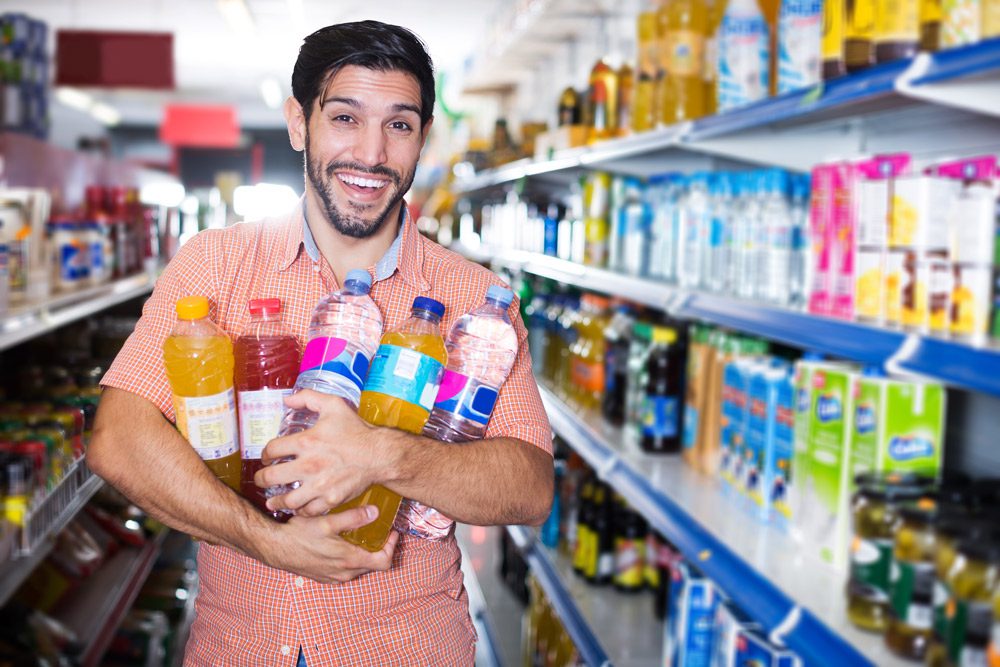 Male standing in store with plastic bottles.