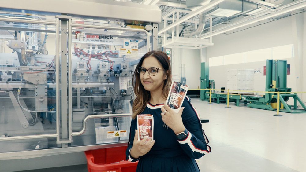 Rashi holds up two plastic packages that state they are ready for recycling