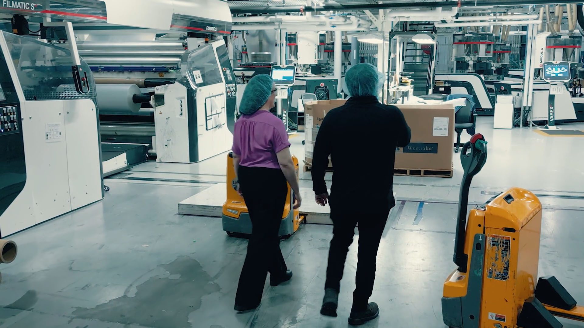 Jennifer walks with colleague through a plastic manufacturing facility