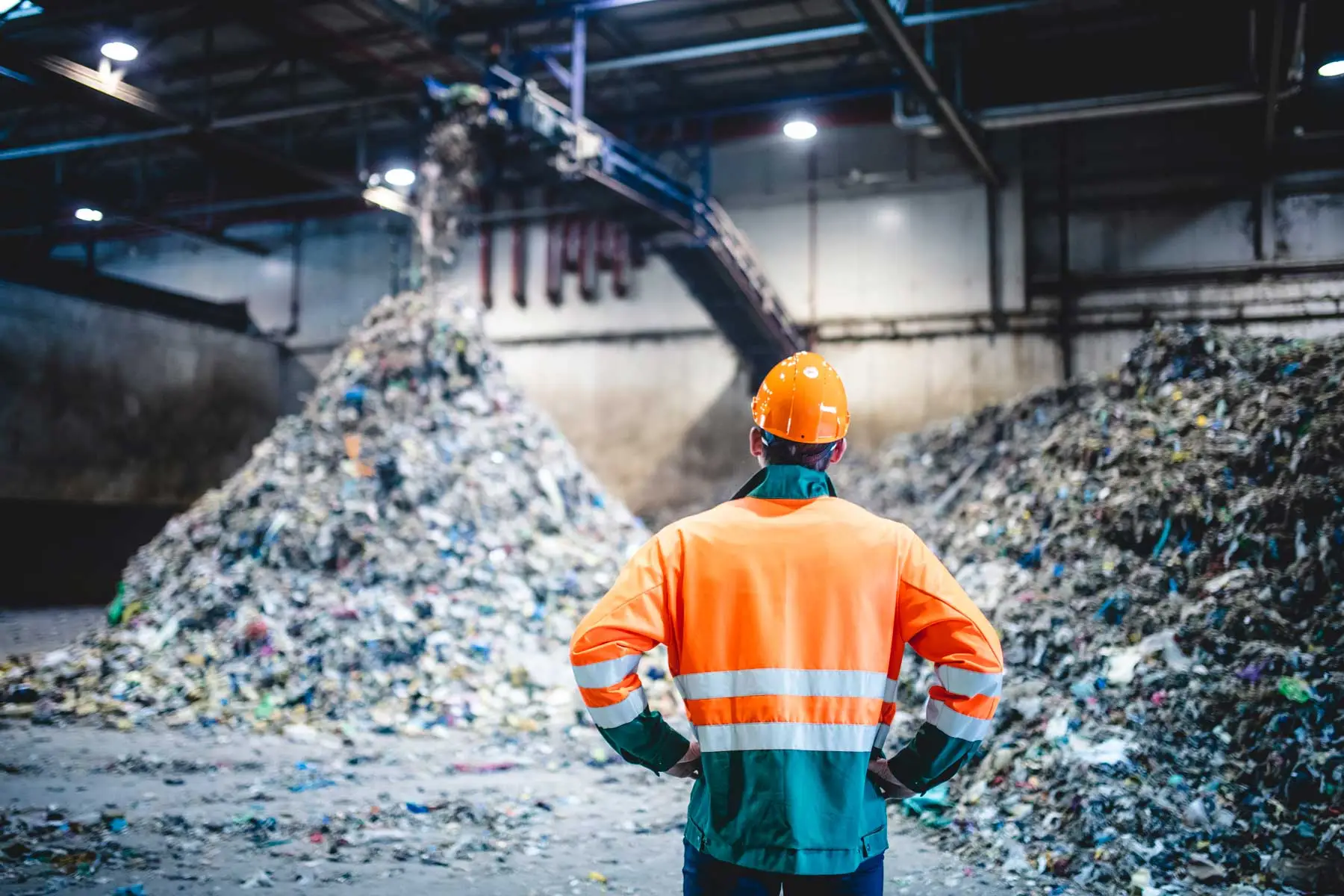 A man looking at a large pile of plastic to be recycled.