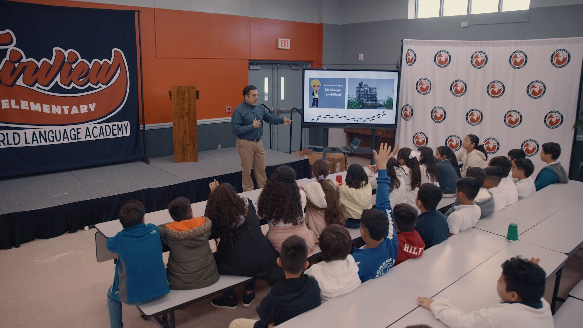 Armando from LDB presenting to school kids with raised hands