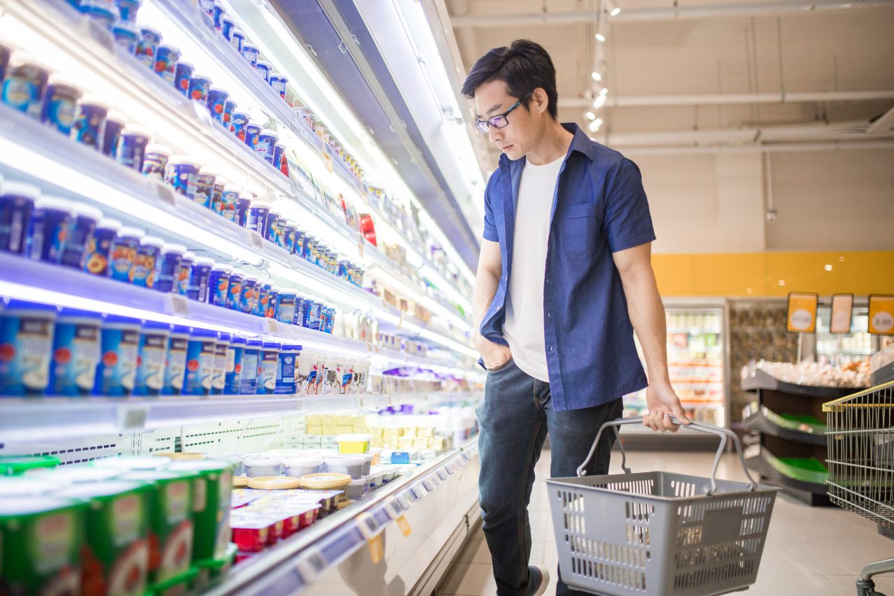 A man holding basket and browses for products in the Frozen Goods Section.