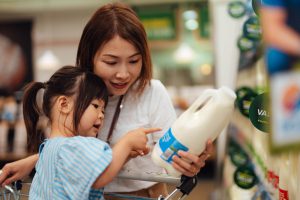 Mother and daughter reading a label on a plastic bottle.