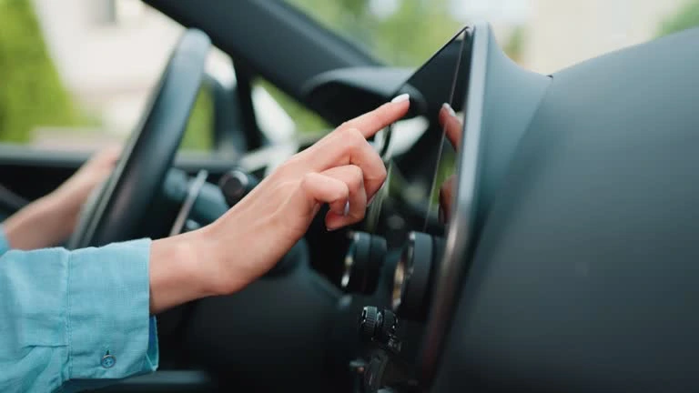 Close up shot hand of woman using touch screen in car setting up the navigation gps application on the touchscreen console.
