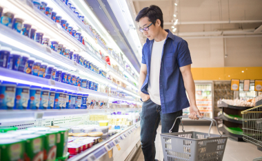 A man holding basket and browses for products in the Frozen Goods Section.
