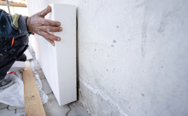 Worker Placing Sheet Insulation to Wall